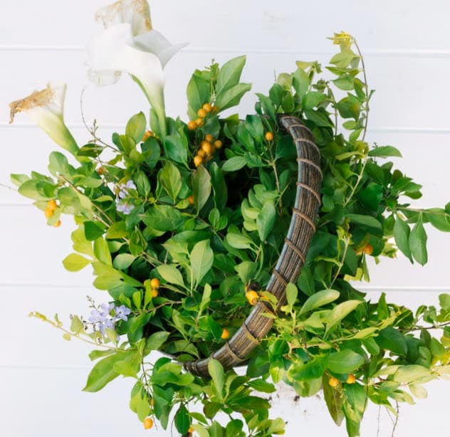 A green leatherleaf and flower arrangement in a basket