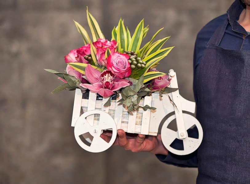 A small white bicycle carrying pink flowers