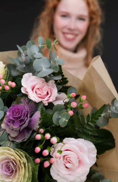 A florist holding roses and eucalyptus