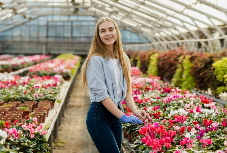 A grower smiling in a long greenhouse aisle