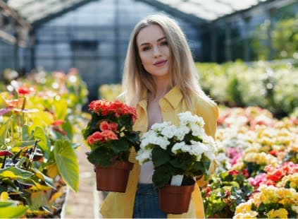 A grower holding two pots of flowers