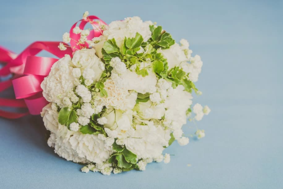 A white bouquet tied with a pink ribbon on a blue background
